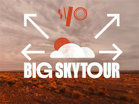 SYO Big Sky Tour written in white text with clouds above in white and arrows pointing outwards background image of a bush landscape on a cloudy day