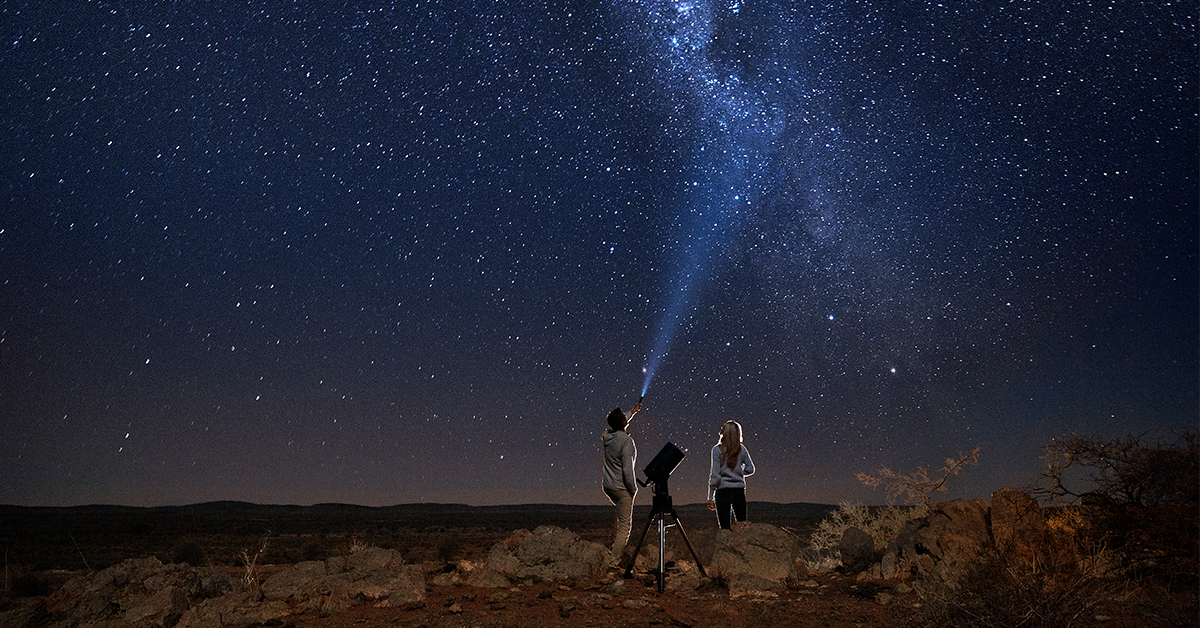 A man shines a torch up at the Milky Way