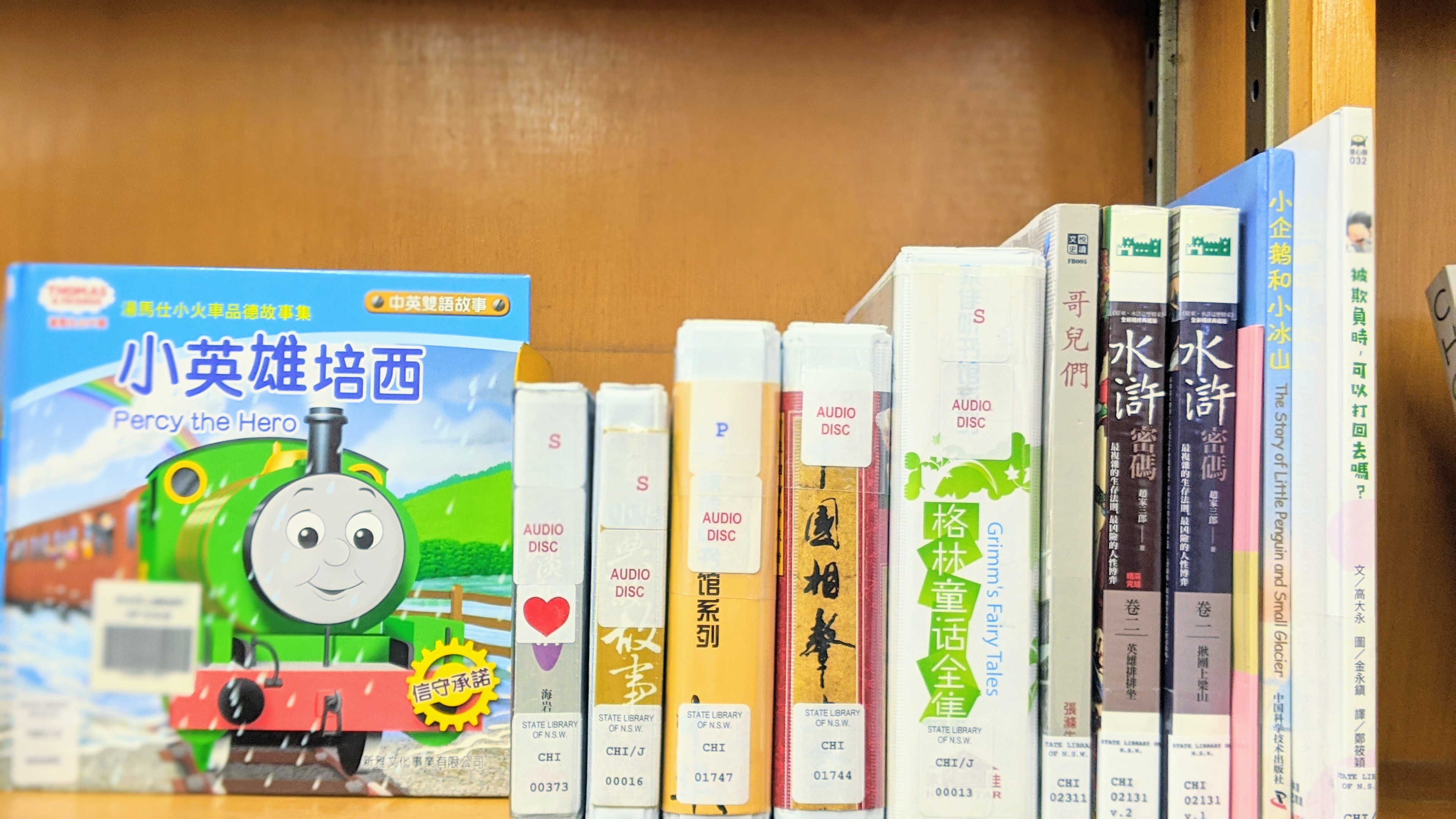 Photograph of the Chinese language books on the shelf, all spine facing camera except Percy the Hero which as an image of 'Percy' a railway locomotive