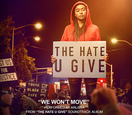 Main character standing in crowd with sign saying The hate u give