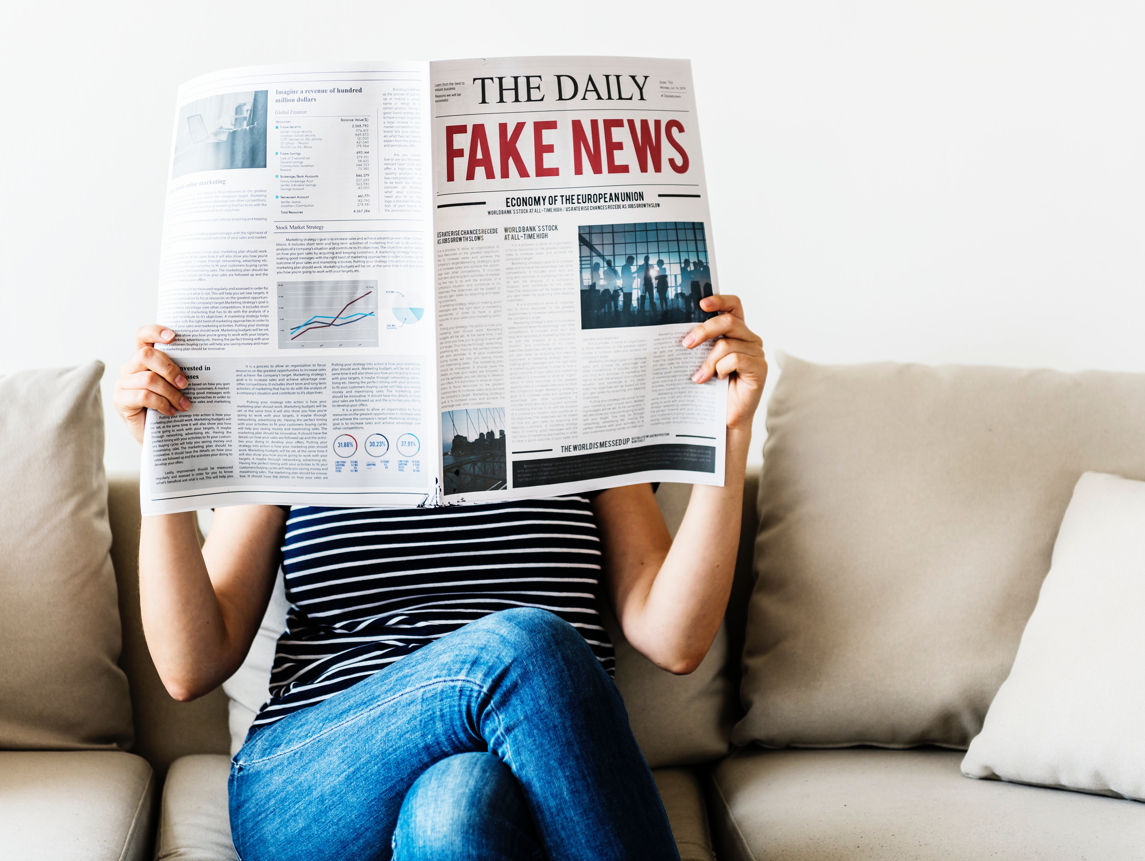 Person reading newspaper with story title Fake news