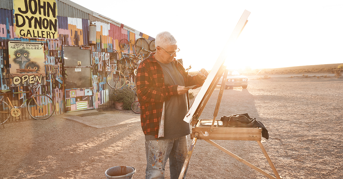 An artist paints as the sun sets behind him
