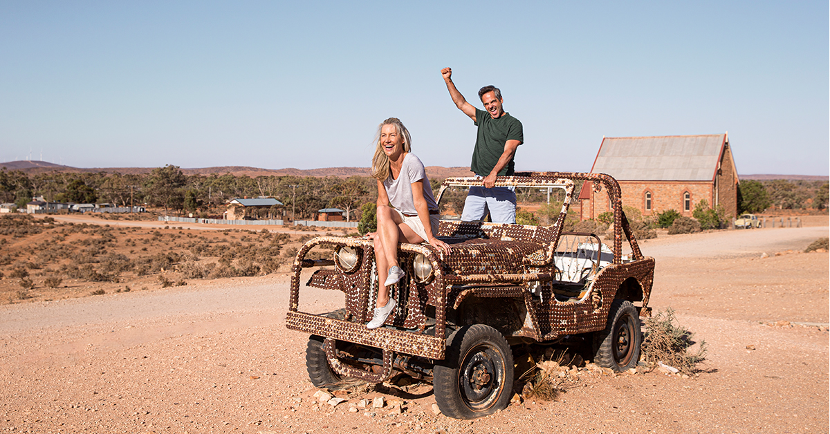 A couple pose with the bottle cap encrusted relic of a car