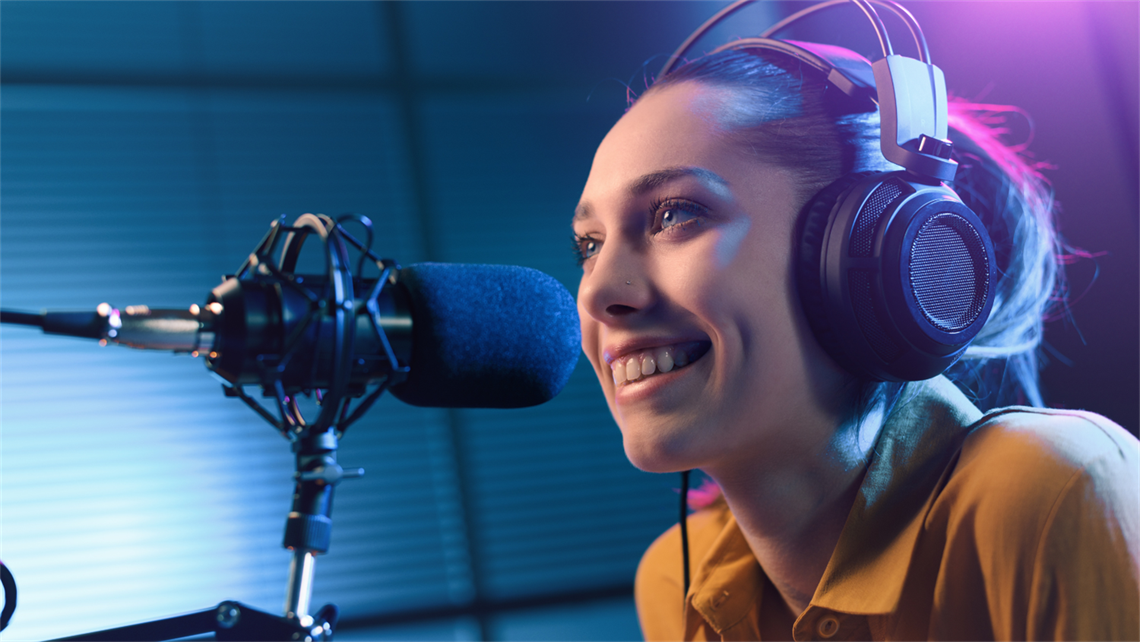 imagwe of a young female with headphones on sitting in a colourful radio booth