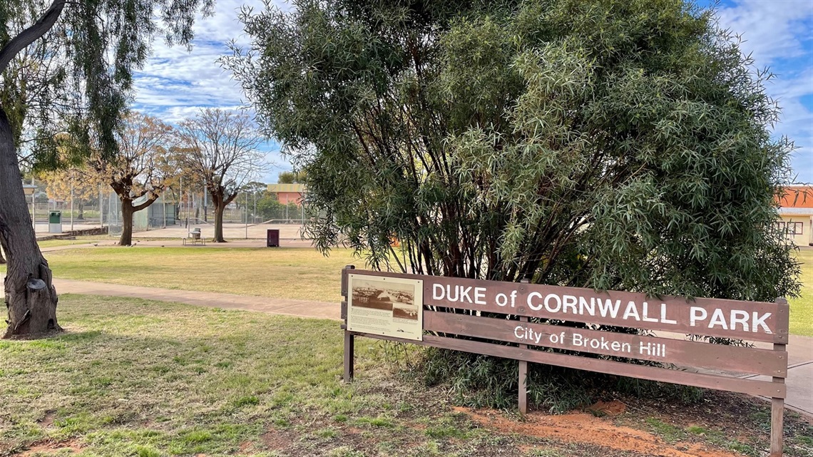 Image of Duke of Cornwell park, showing trees and grass as well as the welcome sign with the park name scribed into it.