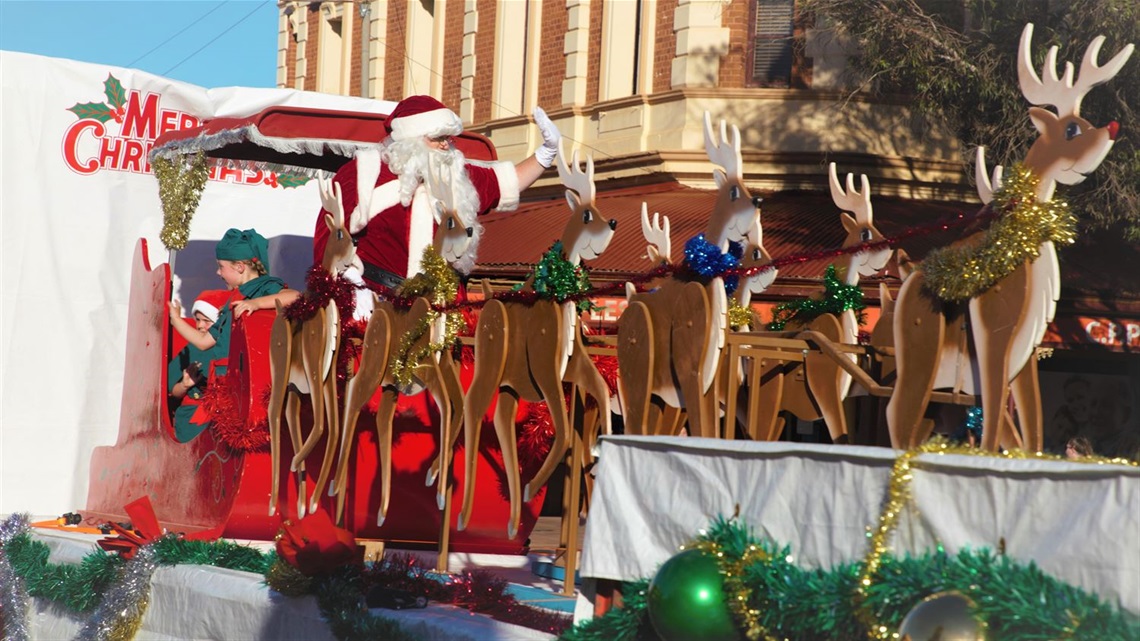 Image of santast sleigh with santa and two elves waving out to the crowd