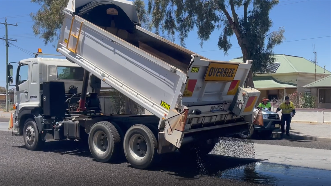 image of truck pouring bitumen out onto the road during a resealing task