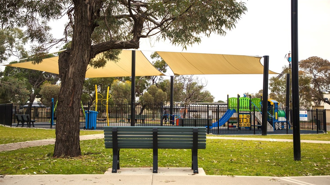 Queen Elizabeth Parks playground area with park bench in front