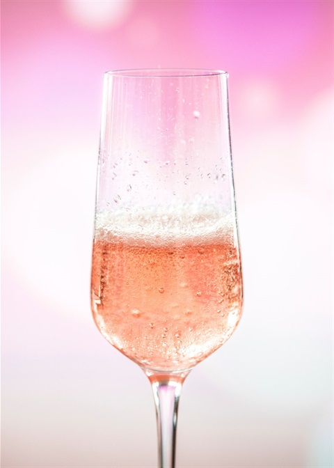 Half full champagne flute with pink background