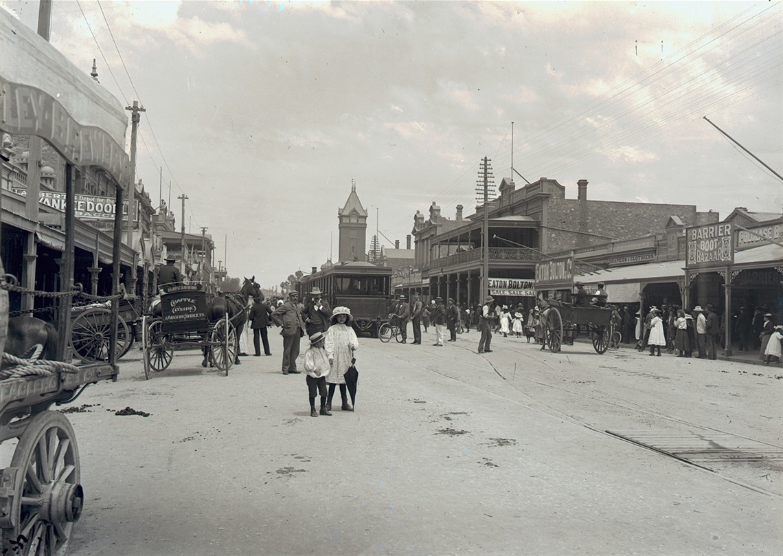 Black and white photo of two girls crossing a busy Argent st