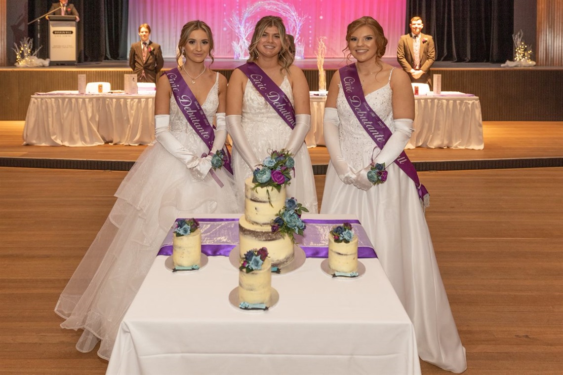 image of three debutantes standing in front of their dubatante cakes at the 2022 broken hill civic ball