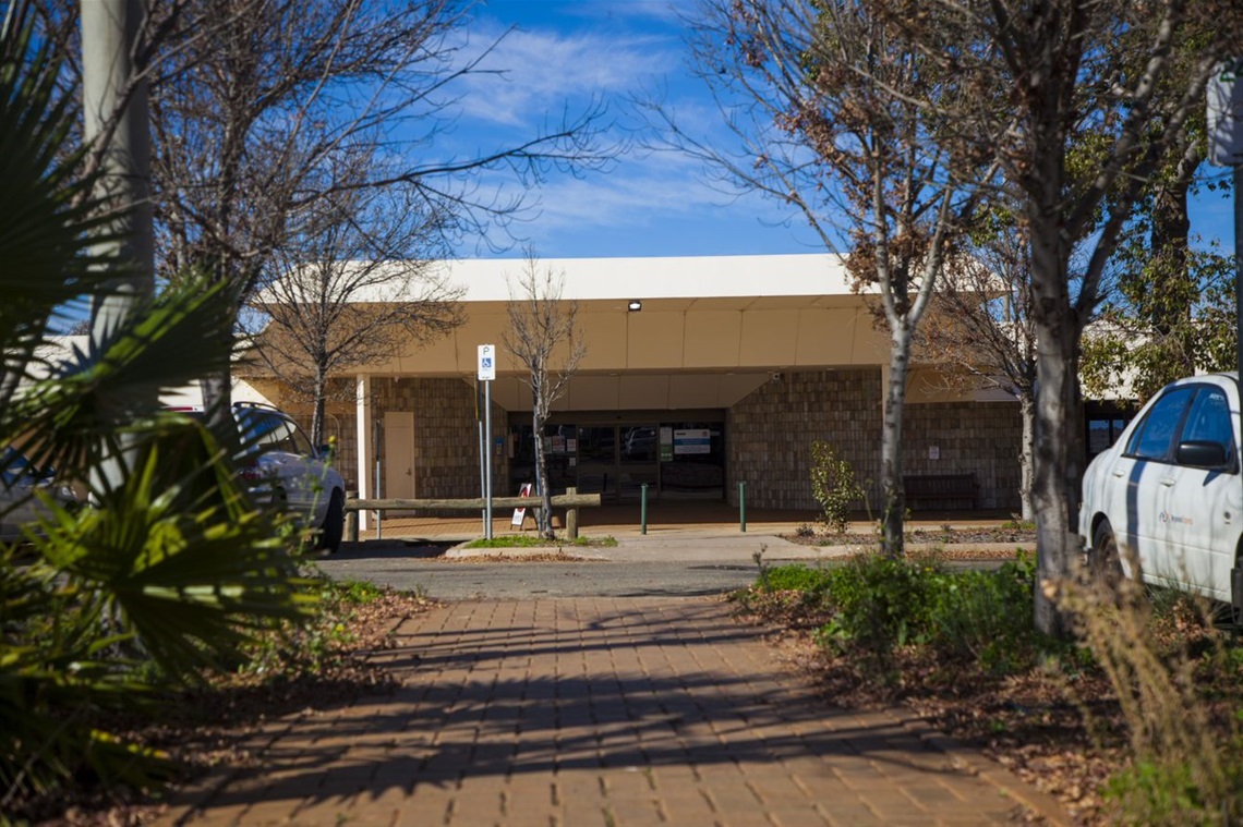 front entrance of the broken hill city airport. you can see foliage on each side of the photo and in the centre, the pathway leading to the glass sliding doors.