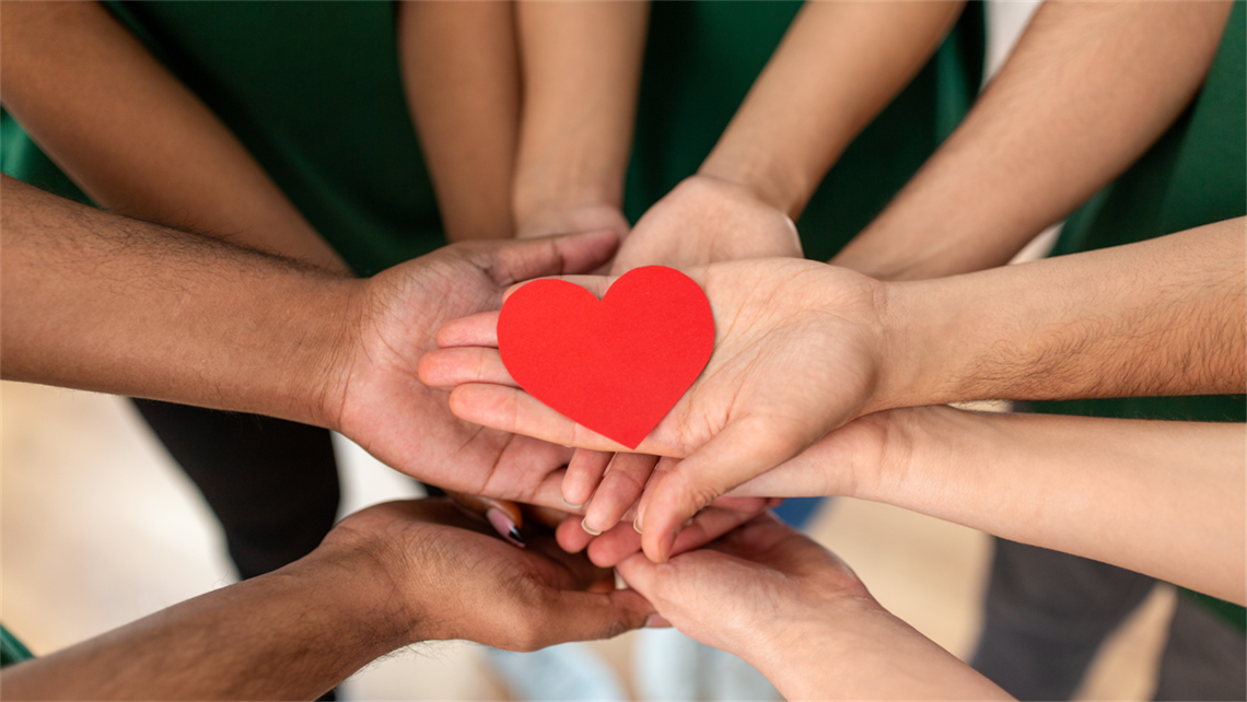 image of hands all coming together into the centre with a red love heart over the top of them.