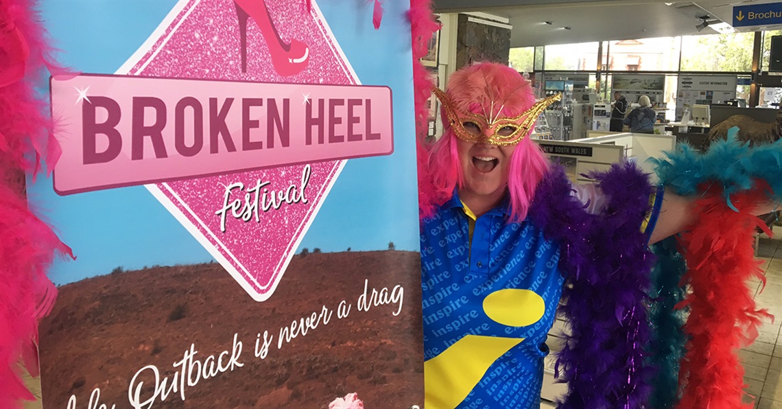 Visitor Information Centre staff member dressed up alongside a Broken Heel Festival sign