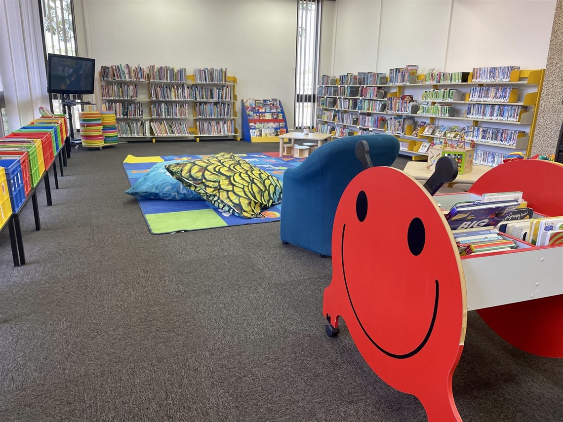 library shelves full of books, a tv in the corner and cushions on the ground of the new temporary library space