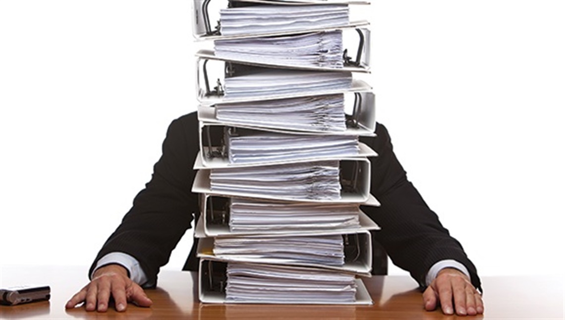 A man sitting at a desk behind a stack of folders
